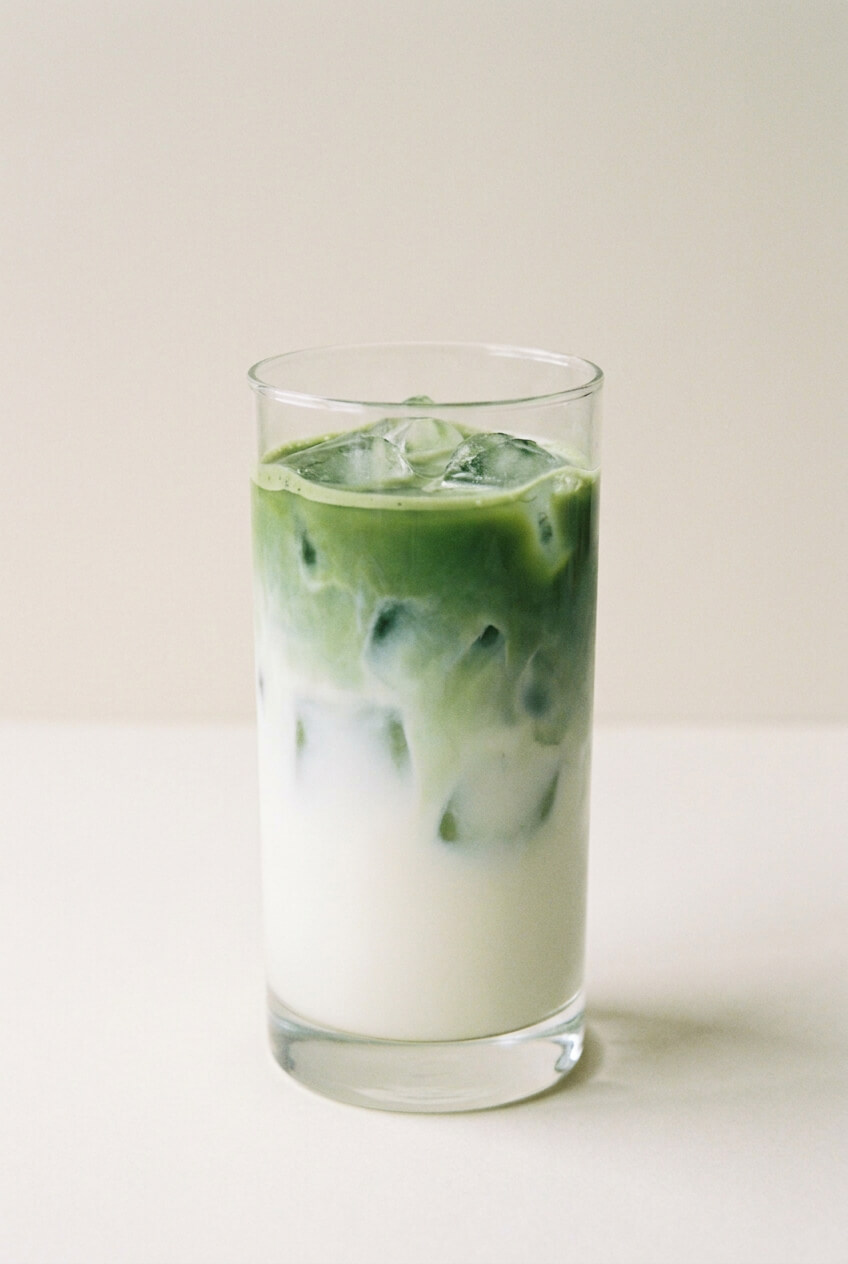 Élénkzöld matcha réteg a hideg tejen a pohárban